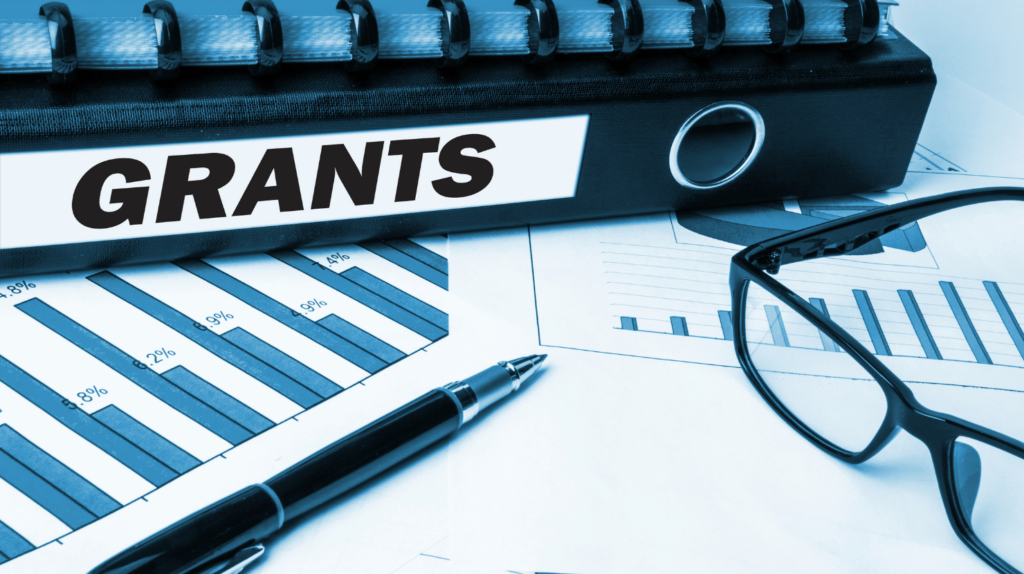 What Is a Business Grant and How Do I Obtain One? An office desk showing paperwork and a folder called "grants"